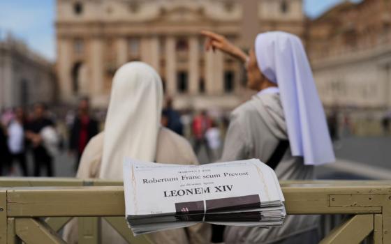 Nuns stand next to copies of L'Osservatore Romano, a Vatican newspaper, with headlines about Pope Leo XIV