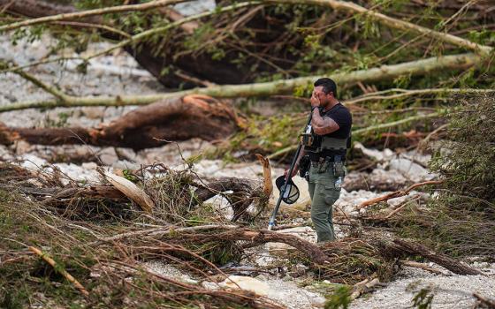 A sheriff's deputy pauses while combing through the banks of the Guadalupe River near Camp Mystic after a flash flood swept through the area Saturday, July 5, 2025, in Hunt, Texas. (AP/Julio Cortez)