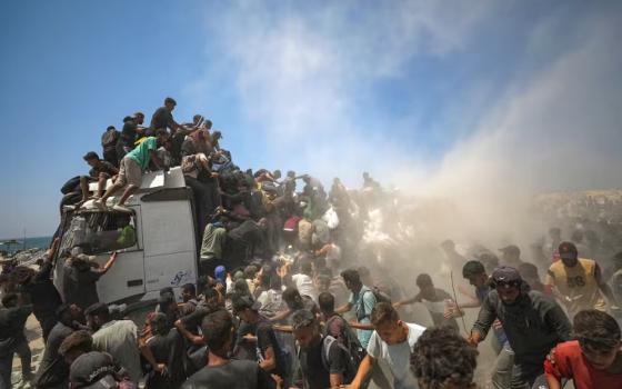 Palestinians try to grab bags of flour from an aid truck near a food distribution point in northern Gaza on July 27. (EPA/Mohammed Saber)