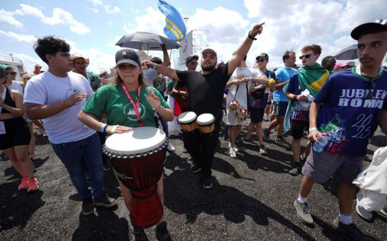 Crowd of young people walking, with person with drum in front