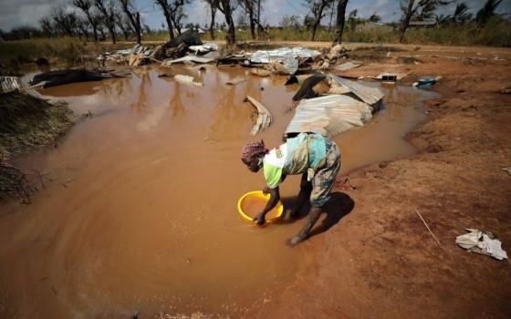 A woman collects water for washing as floodwaters begin to recede in the aftermath of a 2019 cyclone near Beira, Mozambique. Many climate scientists have associated an increased number of natural disasters and their severity with climate change. (CNS/Reuters/Mike Hutchings)