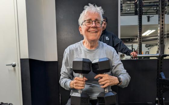 Sr. Pat Farrell holding two 30-pound dumbbells while training with trainer and spotter Jake Levine at The Yard gym. (Erin Edwards)