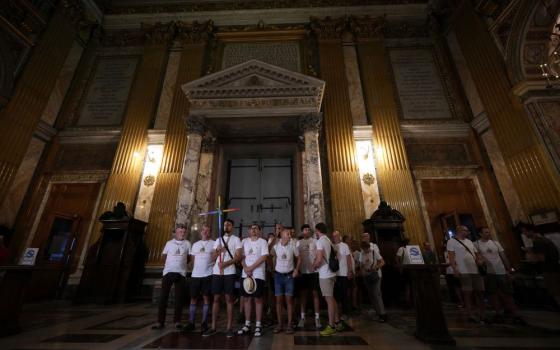 Andrea Mattei, holding a cross, arrives with other members of the LGBTQ+ community to attend a vigil prayer in the Church of the Gesu' in central Rome, Friday, Sept. 5, 2025. (AP Photo/Andrew Medichini)