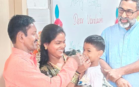 Varalakshmi, a resident of Sumanahalli celebrates her birthday with her husband (left) and daughter. Claretian Fr. George Kannanthanam (right) is also present. (Thomas Scaria)