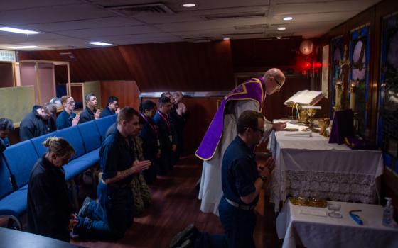Lt. Jacob Meyer, center, a chaplain, reads from the Bible during a Catholic Ash Wednesday service in the chapel aboard the U.S. Navy's USS Ronald Reagan