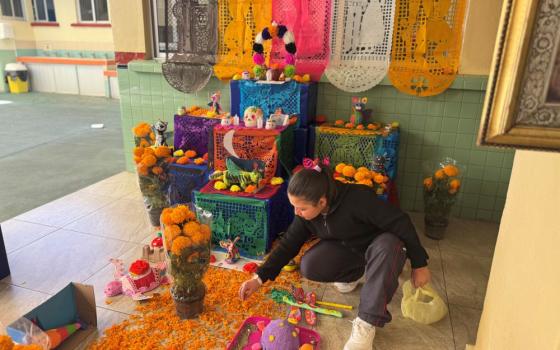 Constanza Flores Valdez, a fifth-grade student at Colegio Tepeyac Mexicano, helps decorate a Day of the Dead altar at her school Oct. 28. (GSR photo/Rhina Guidos)