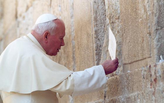 Pope John Paul II places a prayer in a crevice of the Western Wall, Judaism's holiest site, March 26, 2000. Speaking to ecumenical leaders on the historic trip that included visits to Jordan, Israel and the Palestinian territories, the pontiff prayed that the Holy Land would be a homeland to all faiths and peoples. (CNS file photo/Arturo Mari)