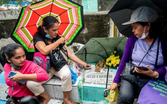 A woman lights a candle on the grave of her mother at the Manila North Cemetery during All Saints' Day in Manila, Philippines, Nov. 1, 2022. (CNS/Reuters/Lisa Marie David)