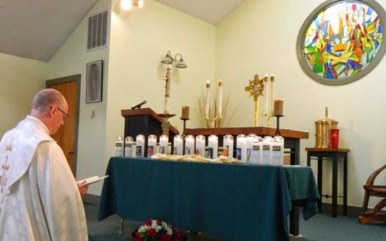 A priest blesses memorial candles lit at an Emmaus Ministry for Grieving Parents retreat held in West Virginia.