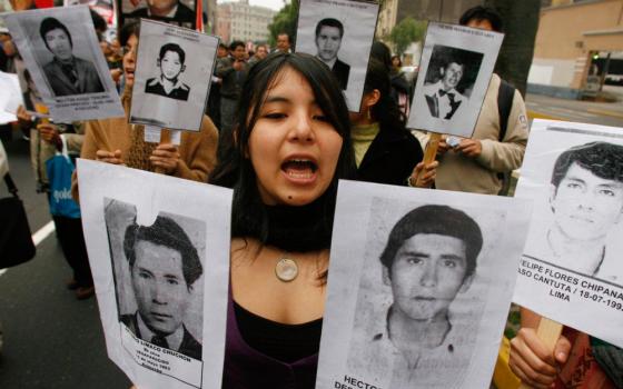During a march in Lima, Peru, Sept. 27, 2007, a woman carries pictures of people murdered during the term of former Peruvian President Alberto Fujimori. Chile extradited Fujimori Sept. 22, 2007, paving the way for a trial in Peru. (CNS/Reuters/Pilar Olivares)