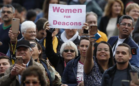 A woman holds a sign in support of women deacons as Pope Francis leads his general audience in St. Peter's Square at the Vatican Nov. 6, 2019. (CNS/Paul Haring)