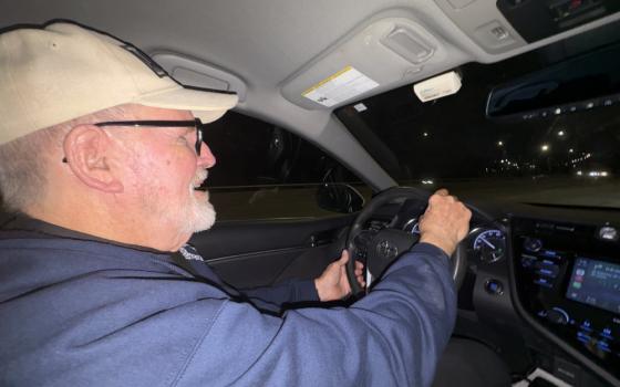 Fr. Dennis Berry drives a young Venezuelan couple and their 8-year-old son back home from the rectory at St. James Parish, where they spent the afternoon doing laundry for themselves and eight other Venezuelans living with them. (NCR photo/Camillo Barone)