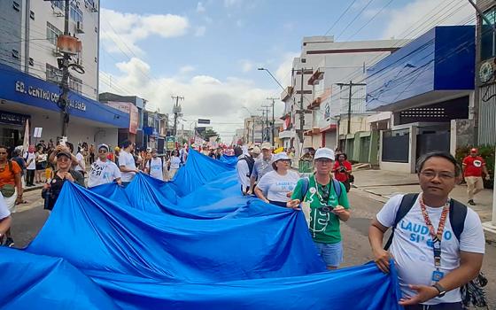 Catholics with the Laudato Si' Movement carry the "River of Hope" banner through the streets of Belém, Brazil, at the global climate march Nov. 15 during the COP30 United Nations climate change conference. (Eduardo Campos Lima)