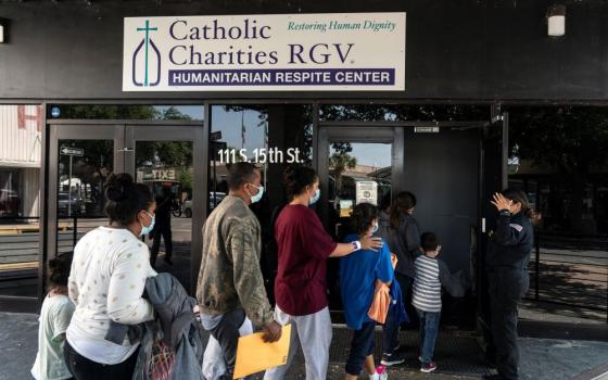 Migrants seeking asylum in the U.S. walk into a temporary humanitarian respite center run by Catholic Charities of the Rio Grande Valley in McAllen, Texas, April 8, 2021. 