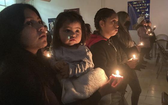 Guests at the Buen Samaritano shelter for migrants participate in a candle lighting ceremony in anticipation of Christmas in Ciudad Juárez, Mexico, across from El Paso, Texas, Dec. 22, 2022. (AP/Morgan Lee)