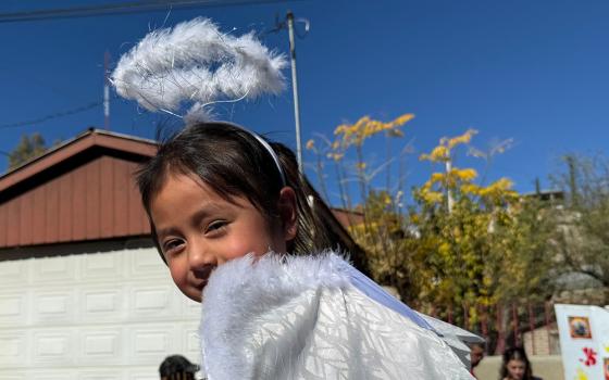 A little girl dressed as an angel and perched on the shoulders of a grown-up participates in a traditional posada procession along the border wall in Nogales, Mexico, on Saturday, Dec. 20. (Anita Snow)