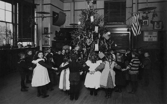 Children hold hands around a Christmas tree at a New York City school, circa 1900 (seligmanonline/The New York Public Library)