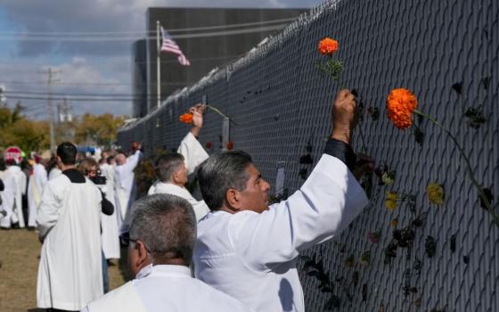 Religious leaders place marigold flowers used on the altar during the service into the fence surrounding the Broadview ICE facility in Chicago Nov. 1 on the day of an outdoor Mass observed by interfaith leaders, community members and volunteers. The Mass was led by Chicago Auxiliary Bishop José María Garcia-Maldonado. (OSV News/Reuters/Leah Millis)
