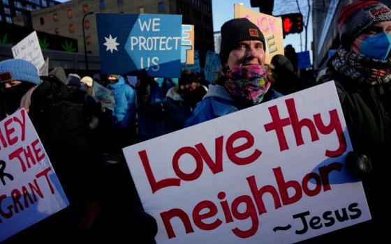 A protester holds a sign reading "Love thy neighbor — Jesus" during a rally against federal immigration enforcement on Friday, Jan. 23, 2026, in Minneapolis. (AP/Angelina Katsanis)