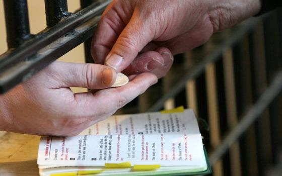 A chaplain distributes Communion to a death-row inmate at Indiana State Prison in Michigan City, Indiana. (CNS/Northwest Indiana Catholic/Karen Callaway)