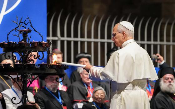 Pope Leo XIV lights a candle during an international gathering for peace attended by leaders of Christian communities and other world religions at the Colosseum in Rome Oct. 28, 2025. The annual International Meeting of Dialogue and Prayer for Peace was organized by the Rome-based Community of Sant'Egidio. (CNS/Lola Gomez)