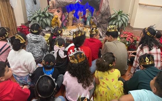 Migrant children wearing golden cardboard crowns gather around a large Nativity scene at a church where the advocacy group Salvavision organized a Three Kings Day celebration in Tucson, Arizona, on Sunday, Jan. 4, 2026. (Anita Snow)