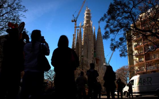 People watch as a crane lifts the upper arm of the cross onto the Tower of Jesus Christ at the Sagrada Familia in Barcelona, Spain, Feb. 20, reaching the basilica's maximum height of 172.5 meters (566 feet). (AP/Emilio Morenatti)