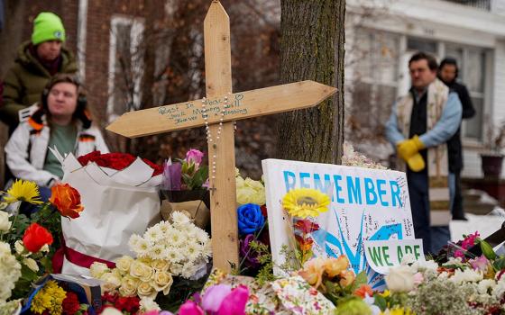 A rosary is draped over a cross as people gather by a makeshift memorial in Minneapolis Jan. 8, 2026, at the scene of the fatal shooting of Renee Nicole Good by a U.S. Immigration and Customs Enforcement agent. (OSV News/Reuters/Tim Evans)