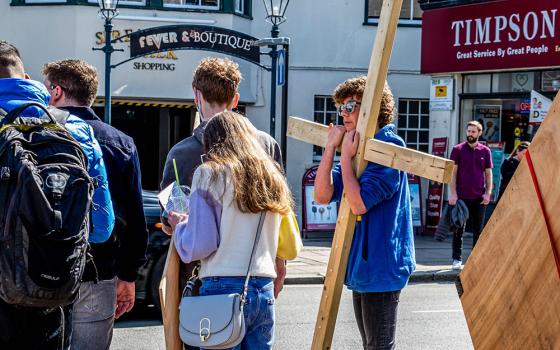 A young man carries a cross as he participates in a Good Friday service in Epsom, Surrey, England, April 15, 2022. (Dreamstime/Martinlee58)
