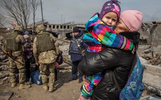 A woman holds a child next to a destroyed bridge during evacuation from Irpin, Ukraine, March 28, 2022, as Russia continued its attack on the country. (OSV News/Reuters/Oleksandr Ratushniak)