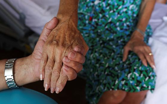 A nurse touches the hand of a patient at the palliative care unit of the Clinic St.-Elisabeth in Marseille, France, May 31, 2024. (OSV News/Reuters/Manon Cruz)