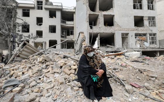 A woman sits amid rubble outside her destroyed apartment in Tehran, Iran, March 12, following an airstrike amid the U.S.-Israeli war with Iran. (OSV News/Reuters/Alaa Al Marjani)
