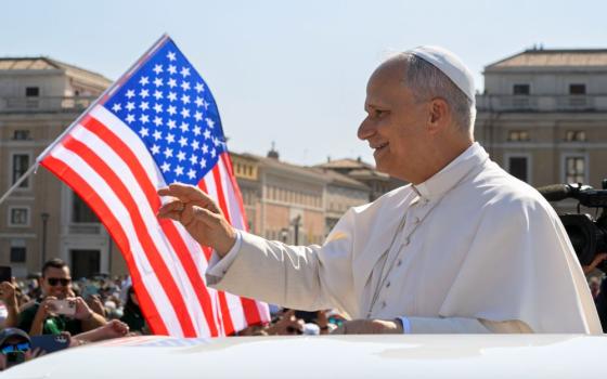With a U.S. flag in the background, Pope Leo XIV waves to the crowd from the popemobile as he rides around St. Peter's Square at the Vatican before his weekly general audience Aug. 6, 2025. (CNS/Vatican Media)