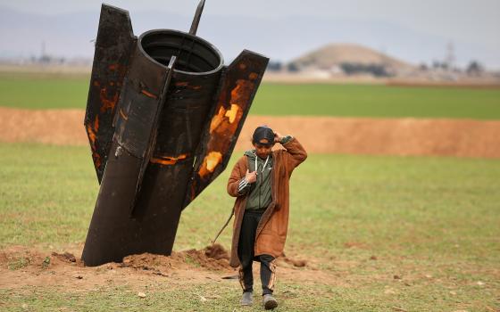 A shepherd boy walks away from an unexploded Iranian projectile that landed in an open field in the outskirts of Qamishli, eastern Syria, March 4, 2026. (RNS/AP/Baderkhan Ahmad)