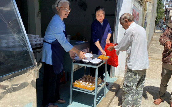 Sr. Trần Thu Hà and Sr. Nguyễn Thị Hường, of the Lovers of the Holy Cross of Dalat greet people as they line up for hot meals at the Kitchen of Love in Bao Loc, Lam Dong, Vietnam, on May 5, 2023. (Sr. Nguyễn Hồng Ân)