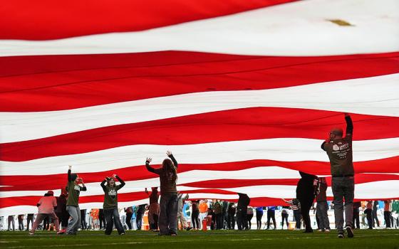 People support a large American flag on the field before the Fiesta Bowl NCAA college football playoff semifinal game between Miami and Mississippi Jan. 8, 2026, in Glendale, Ariz. (AP/Ross D. Franklin)