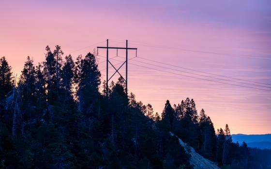 Power lines and a pylon are seen at dawn in the mountains of Montana. (Dreamstime/Brian Grimmer)