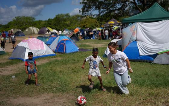 A volunteer plays soccer with children at Francisco de Miranda Park in Caracas, Venezuela, where people whose homes were damaged in the earthquakes are camping, Wednesday, July 1, 2026. (AP/Matias Delacroix)