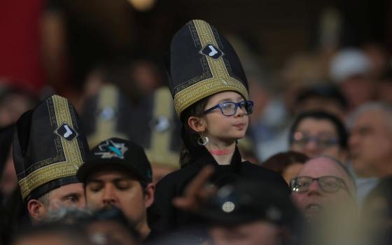 A fan wears a promotional pope hat during a baseball game between the Cincinnati Reds and Chicago White Sox, Aug. 11, 2026, in Chicago. Pope Leo's beloved White Sox lost to the Cincinnati Reds, 5-4. (AP/Melissa Tamez)