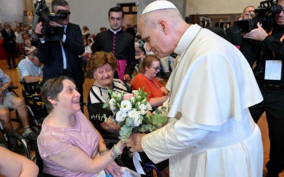 Pope Leo XIV receives a bouquet of flowers from a woman during a meeting with people experiencing illness or disabilities and those receiving support from Caritas in the city's cathedral in Rimini, Italy, Aug. 22, 2026. (CNS/Vatican Media)