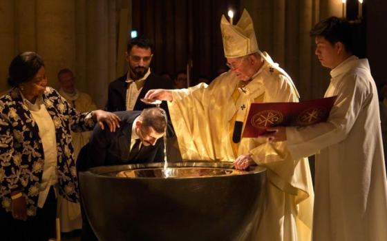 Paris Archbishop Laurent Ulrich baptizes an adult man in the baptismal font of Notre Dame Cathedral in Paris during Easter Vigil April 4, 2026. (OSV News/Courtesy Archdiocese of Paris/Liam Hoarau)