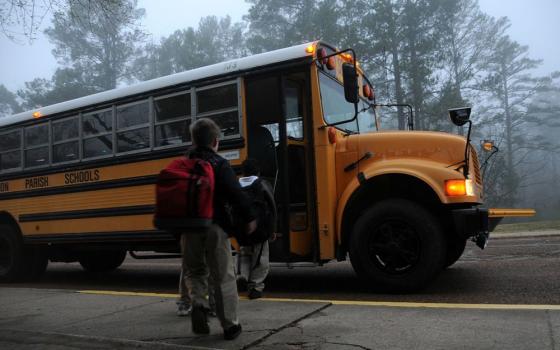Children wait to board school bus. 
