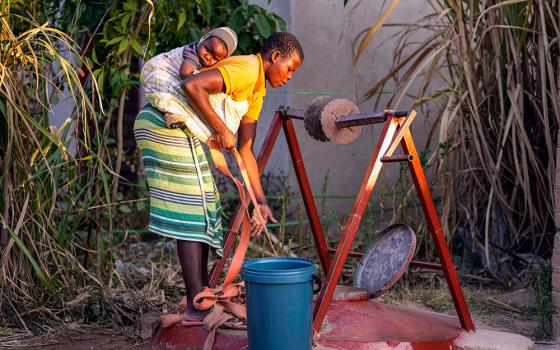 A woman with a baby strapped on her back fetches water from a well in Epworth, a poor neighborhood on the outskirts of Harare, Zimbabwe, June 15, 2022.(AP/Tsvangirayi Mukwazhi)