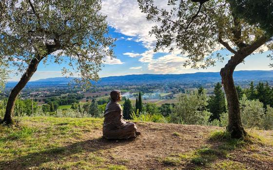 A bronze sculpture of St. Francis of Assisi looks out over the medieval Italian town outside the Church of San Damiano on Oct. 4, 2025. (NCR photo/Brian Roewe)