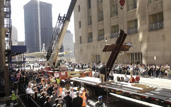 Construction workers Oct. 5, 2006, remove a 20-foot cross formed by steel beams that was recovered from the rubble after the Sept. 11, 2001, attacks brought down the World Trade Center in New York. (OSV News/Reuters/Chip East)