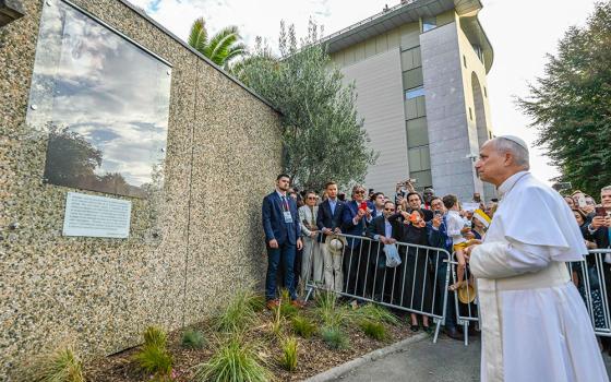Before meeting with bishops representing the French bishops' conference, Pope Leo XIV stops for a moment at a plaque featuring a quotation from a survivor of abuse in Lourdes, France, Sept. 27, 2026. (CNS/Vatican Media)