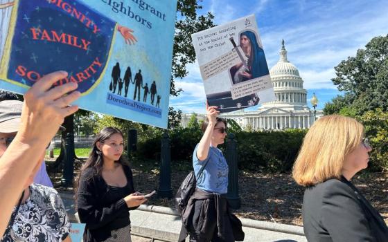 A protester holds a poster depicting the Seven Sorrows through the lens of modern immigrants' experiences during an event Sept. 15 in Washington. (Emma Cieslik)