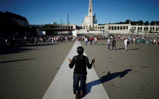 A pilgrim prays near the Marian shrine of Fátima in central Portugal May 12, 2019. In 1917, three shepherd children reported apparitions of the Virgin Mary in the fields of the Cova da Iria quarter in Fátima. (OSV News/Reuters/Pedro Nunes)