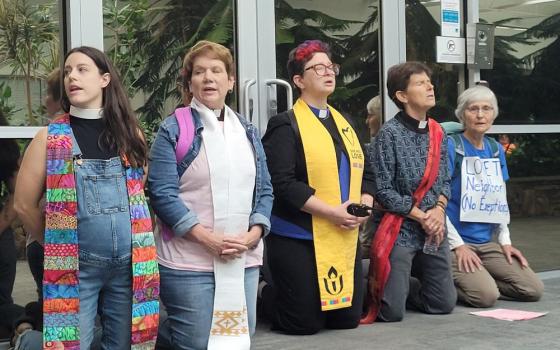 Faith leaders kneel to block an entrance to a building that houses the National Criminal Analysis and Targeting Center, Friday, Sept. 4, 2026, in Williston, Vermont. (RNS/Courtesy photo)