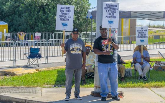 Striking International Longshoremen's Association workers stand on the picket line with signs near the entrance to Port of New Orleans Oct. 2, 2024. (Dreamstime/William Morgan)